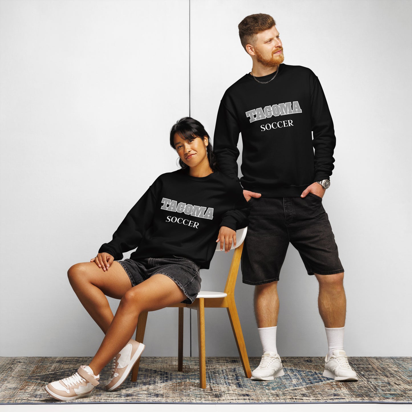 Couple wearing a black Tacoma Soccer TCC Titans sweatshirt.