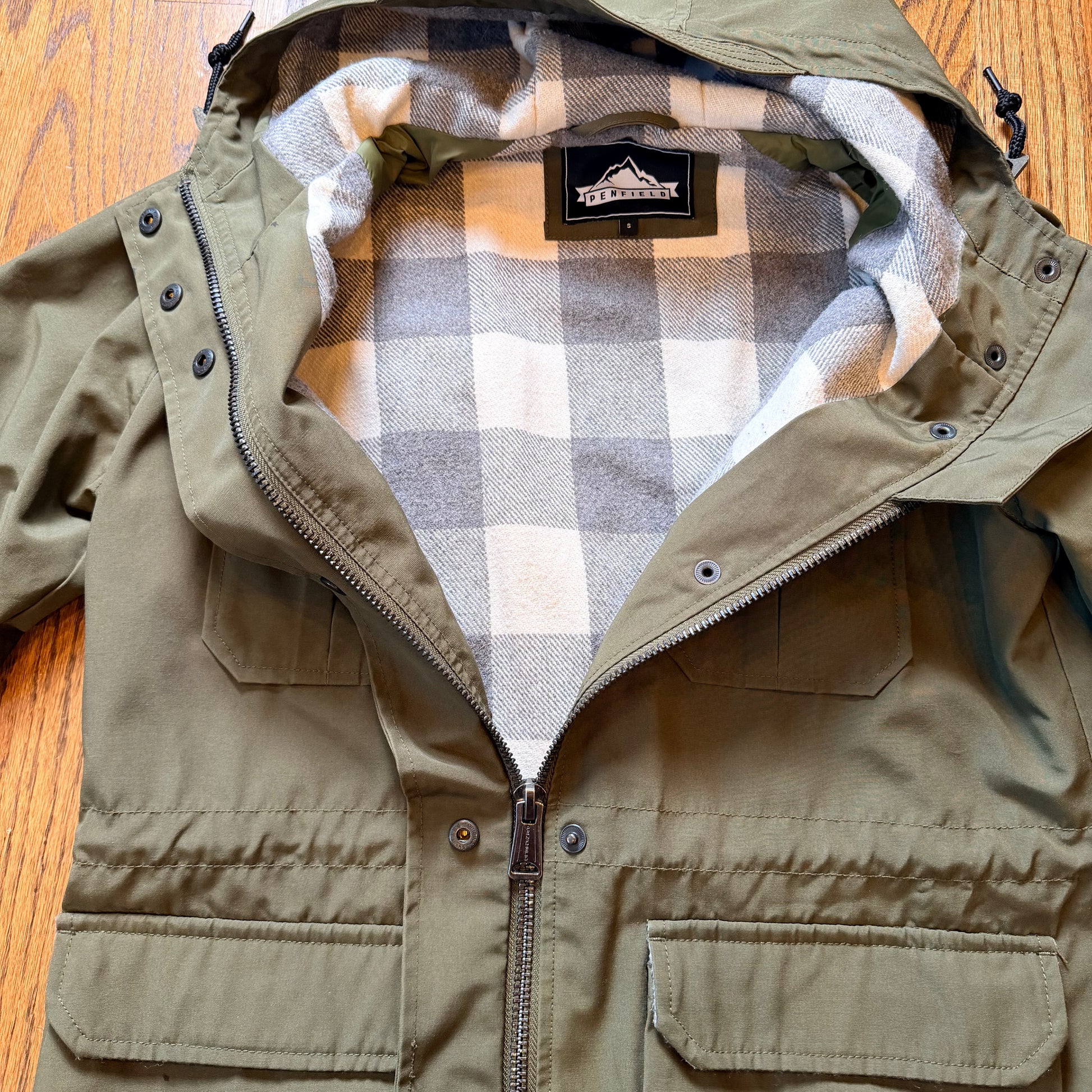 Green jacket with plaid lining on a wooden surface