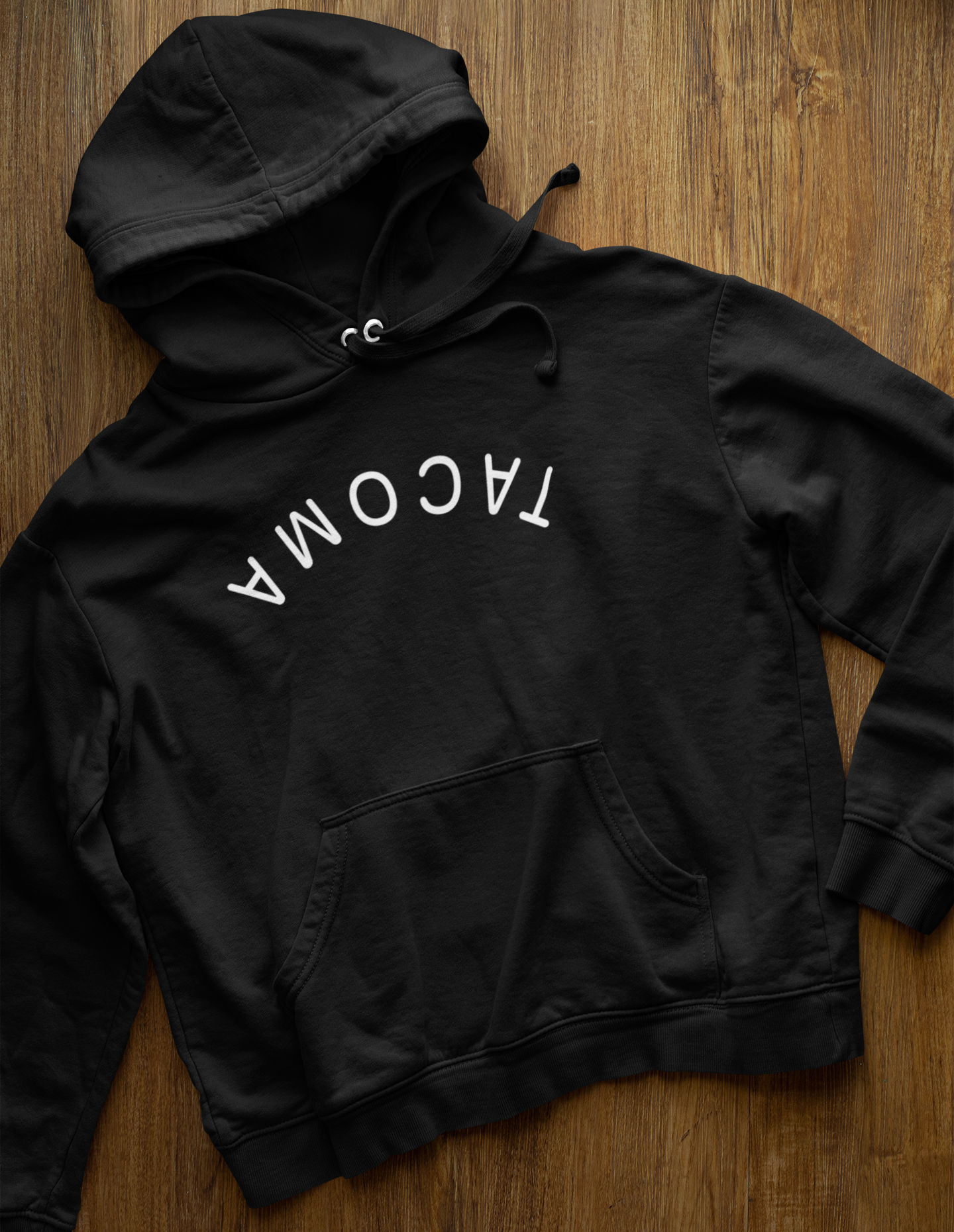 Black Tacoma Flipped Hoodie with white arched text on wooden background
