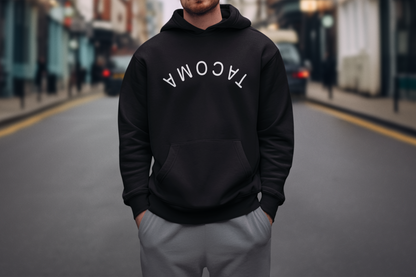 Person wearing a black hoodie with 'TACOMA' text on a blurred street background
