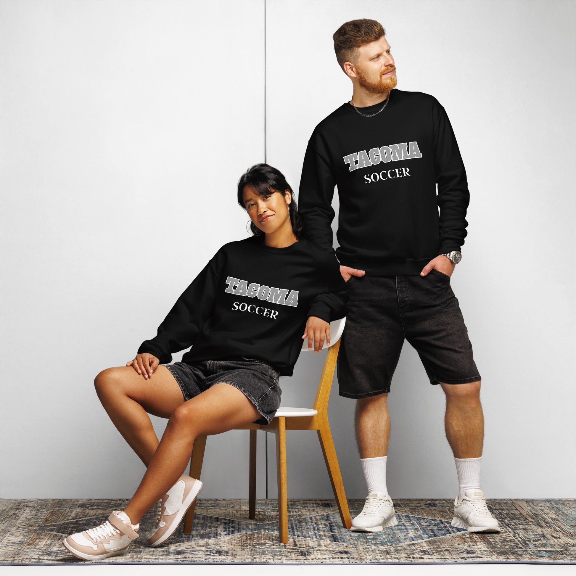 Couple wearing a black Tacoma Soccer TCC Titans sweatshirt.