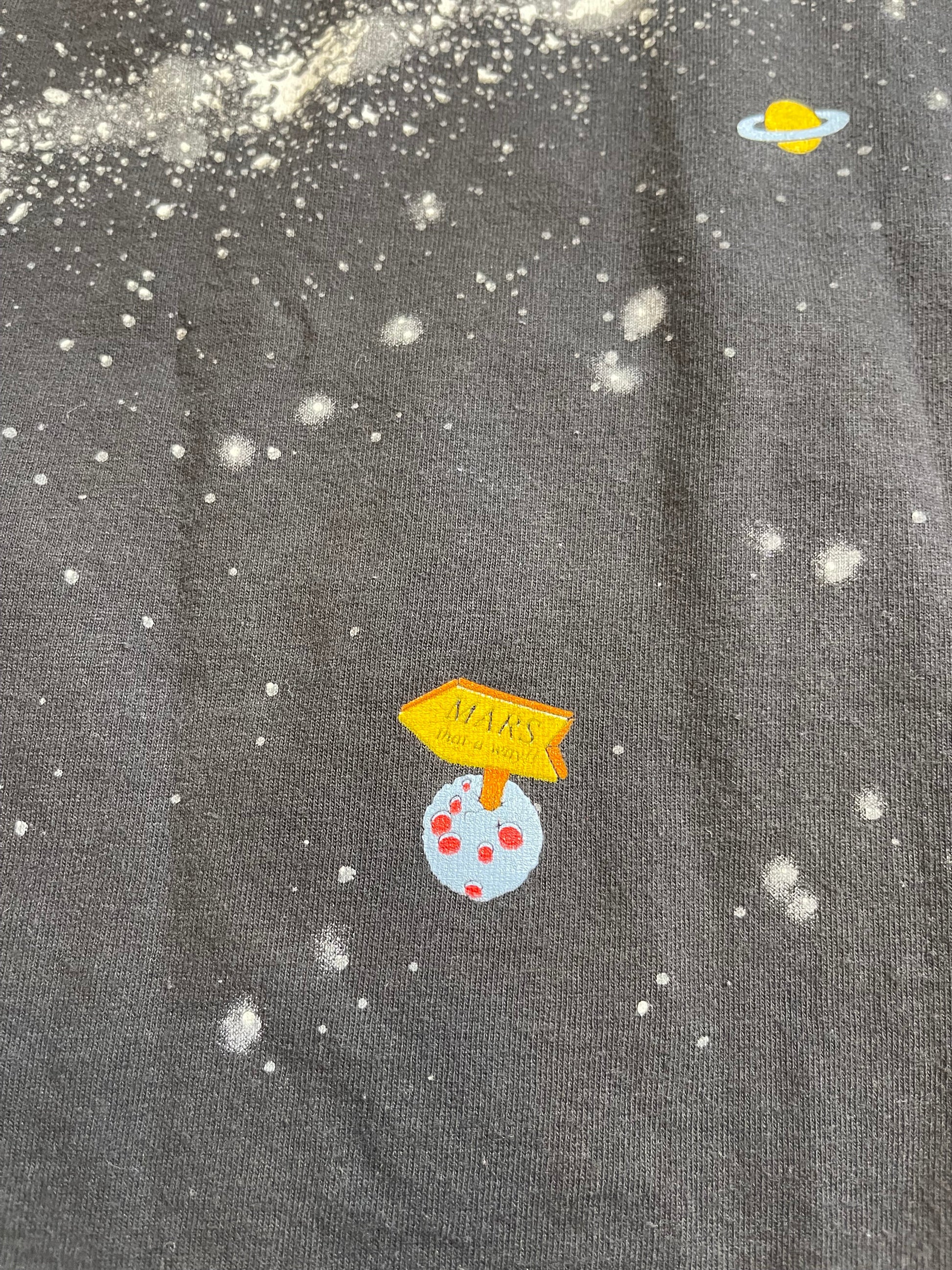 Textured fabric with cartoonish space-themed decorations including planets and stars.